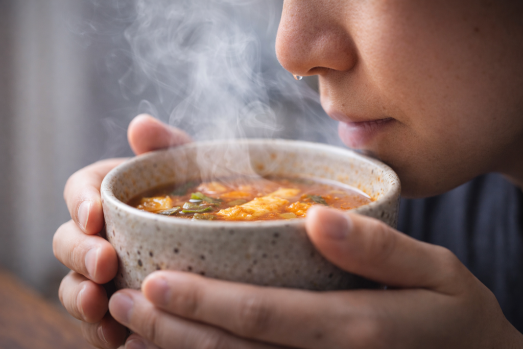 🍜 뜨거운 국물을 먹으면 왜 콧물이 나올까 1 김이 나는 뜨거운 국물을 들고 있는 사람의 얼굴 근접 장면
